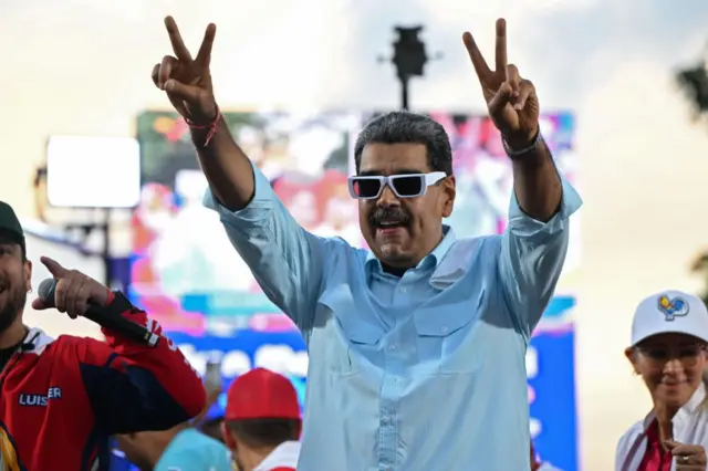 Nicolás Maduro, con gafas de sol, hace un gesto de victoria. 