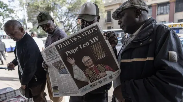 A group of men at a news stand with one of them holding up the Daily Nation. The headline is about Pope Leo XIV.