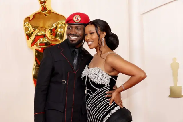 Bobi Wine, coiffé de son béret rouge caractéristique et vêtu d'un costume noir, pose pour une photo avec sa femme.