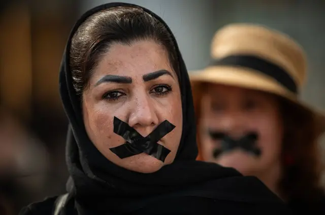 د ۲۰۲۵ کال د اګسټ ۱۵- اسپانیا کې يوه مېرمن چې پر خوله يې ټېپ لګولی، په چوپتیا کې په افغانستان کې د ښځو او نجونو لپاره د بنسټيزو حقونو د له لاسه ورکولو پر ضد اعتراض کوي. د اګست ۱۵مه هغه ورځ ده چې طالبان په افغانستان کې واک ته له راستنېدو څخه څلور کاله پوره شول. 