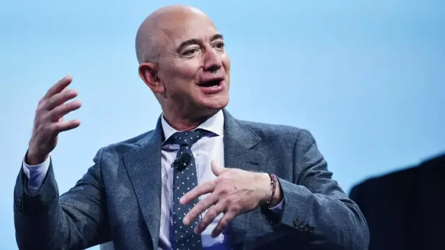 Jeff Bezos gesticula enquanto fala, sentado