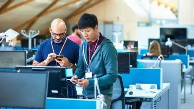 Homem usando celular e computador