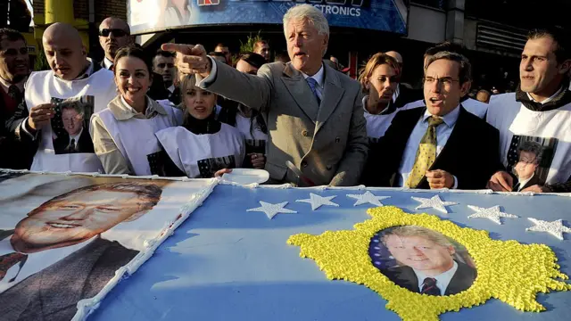 El expresidente Bill Clinton saluda a kosovares de la etnia albanesa frente a una torta gigante preparada en su honor durante una visita que hizo a Pristina, 1 noviembre de 2009