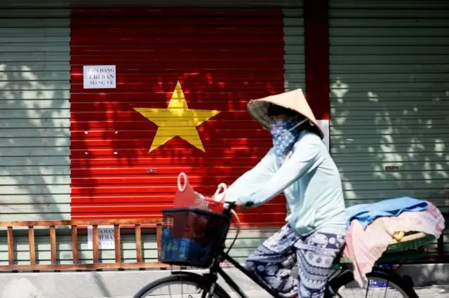 Một người phụ nữ đeo khẩu trang đi xe đạp trên đường phố ở Hà Nội, Việt Nam, ngày 19 tháng 7 năm 2021.
