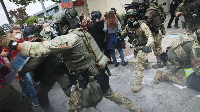 Miembros del Departamento de Seguridad Nacional, la Patrulla Fronteriza y la policía se enfrentan a manifestantes frente a un centro del Servicio de Inmigración y Control de Aduanas (ICE) el 4 de octubre de 2025 en Portland, Oregón.