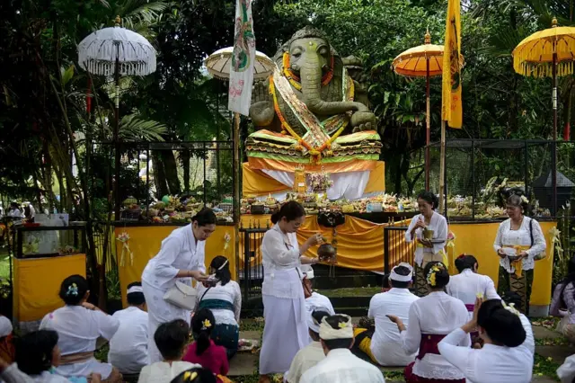 Tokoh agama Hindu Bali memercikkan air suci pada upacara Pujawali ke-20 di Parahyangan Agung Jagatkartta di Bogor, Jawa Barat, Indonesia, pada 7 September 2025.