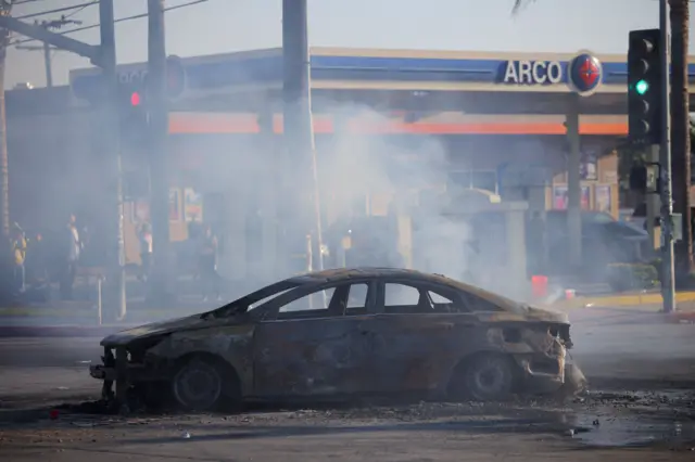 Um carro destruído na estrada durante confronto entre a polícia e manifestantes após detenções pelo Serviço de Imigração e Alfândega (ICE), na cidade de Paramount, no Condado de Los Angeles, Califórnia, EUA, em 7 de junho de 2025.
