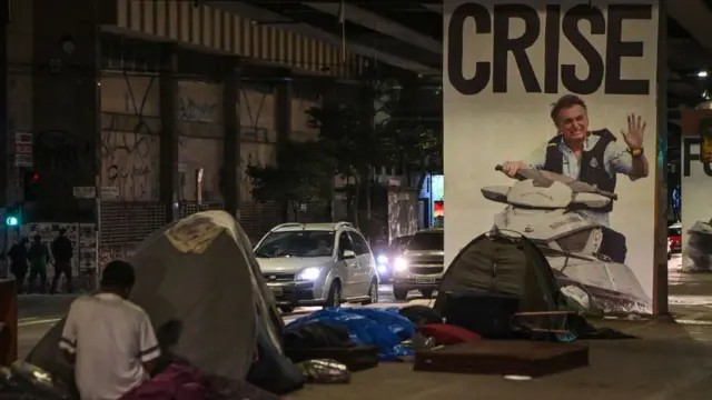 Cartazjames rodriguez fifa 23protesto afixado nas pilastras do Minhocão, no centrojames rodriguez fifa 23São Paulo, diz CRISE sobre uma imagemjames rodriguez fifa 23Bolsonaro andandojames rodriguez fifa 23jet ski. Em frente ao cartaz, pessoasjames rodriguez fifa 23situaçãojames rodriguez fifa 23rua dormemjames rodriguez fifa 23barracas