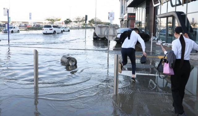مشاة يسيرون وسط مياه الفيضانات في دبي، الإمارات العربية المتحدة، 19 أبريل/نيسان 2024.