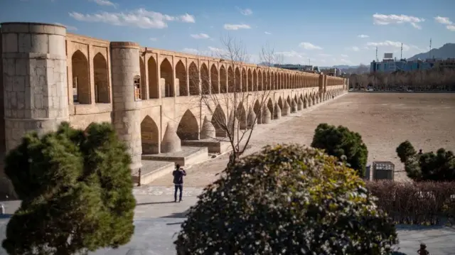 مردی ایرانی در حاشیه رودخانه خشک شده زاینده رود ایستاده و نمایی از پل تاریخی سی و سه پل (۳۳ پل) در شهر تاریخی اصفهان، ایران، در ۲۲ فوریه ۲۰۲۵ به تصویر کشیده شده است.شنبه ۴ اسفند ۱۴۰۳
