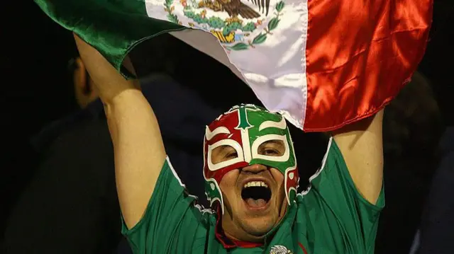 Grito de un hombre con una mascara con los colores de la bandera de México.