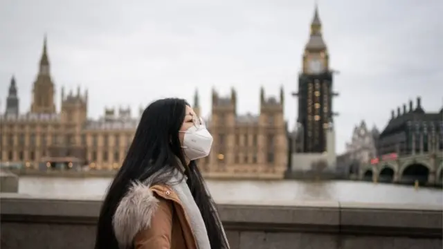 A woman wearing a face mask walks near the Houses of Parliament, in Westminster, London, after new restrictions have come into force to slow the spread of the Omicron variant of coronavirus. Picture date: Thursday December 16, 2021