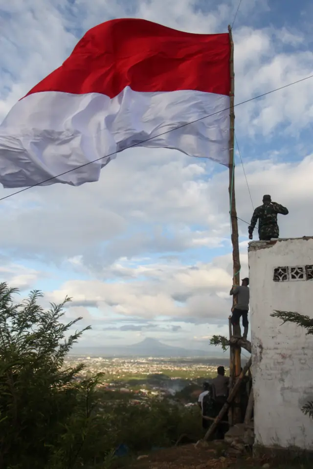Prajurit TNI Koramil Peukan Bada bersama warga mengibarkan bendera Merah Putih di Bukit Cot Aneuk Glee, Kabupaten Aceh Besar, Aceh, Kamis (16/08) dalam rangka menyambut HUT ke-73 RI.