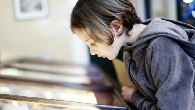 فتى يدقق النظر في معروضات أحد المتاحف