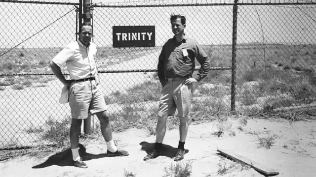 Dos hombres junto a un cartel de Trinity