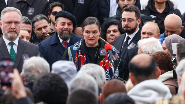 Kalabalığın içinde Tuna Ortaylı Kazıcı önündeki mikrofona konuşuyor. 