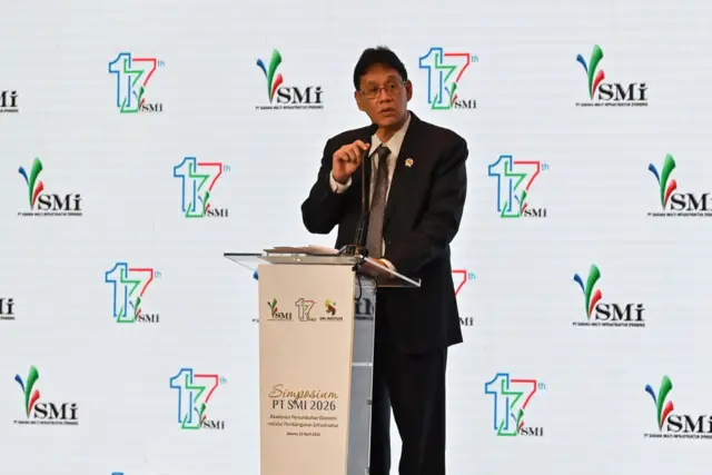 Menteri Keuangan Purbaya Yudhi Sadewa berdiri di belakang podium di atas panggung, menyampaikan pidato saat menghadiri Simposium PT SMI 2026 di Jakarta, Rabu (22/04).