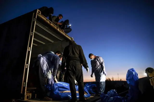 لفافات زرقاء لجثث يتم إنزالها من شاحنة