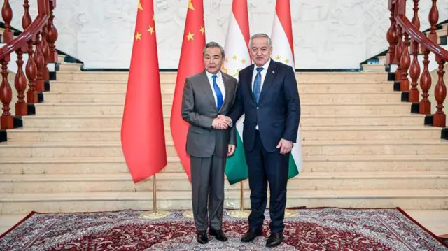  سراج‌الدین مهرالدین وزیر خارجه تاجیکستان در حالی که با وانگ یی وزیر خارجه چین دست داده است.