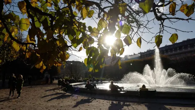 Orang-orang menikmati sore yang cerah di taman Palais Royal di Paris.