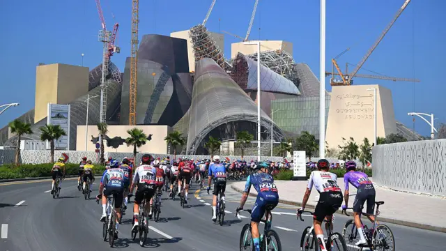 Un grupo de ciclistas pasa frente a un museo de arquitectura moderna en Abu Dabi