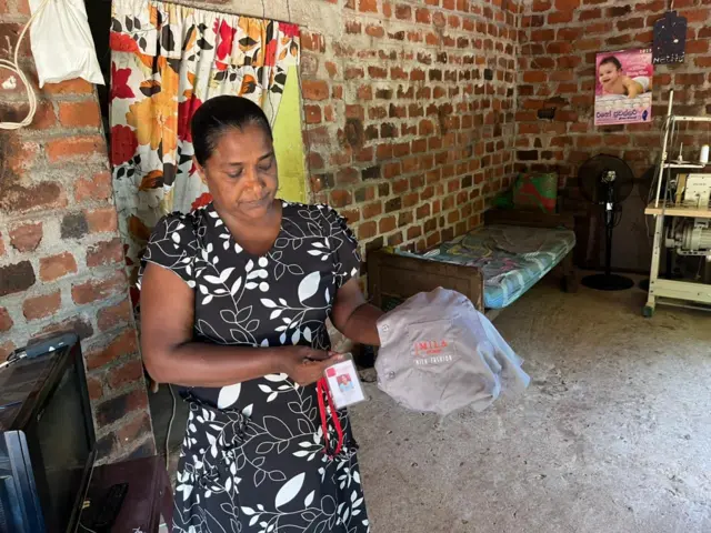 ඇගේ නිල ඇඳුම සහ ආයතනික හැඳුනුම්පත පෙන්වන ගීතිකා