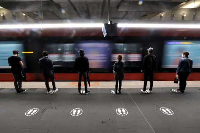 People stand on markers on a tramway platform