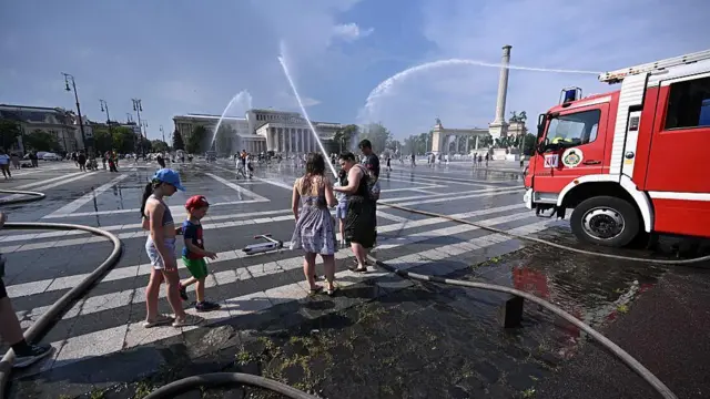 Strażacy używają węży strażackich, aby schłodzić ludzi na budapeszteńskim Placu Bohaterów podczas ekstremalnej fali upałów 30 czerwca 2026 roku.