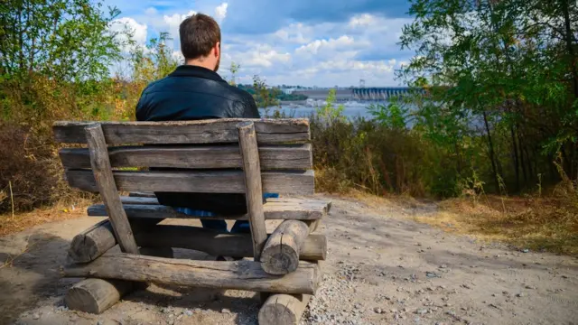 Un hombre sentado en un banco, visto de espaldas