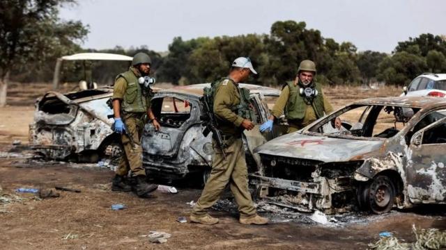 Soldados israelenses circulam em meio a carros queimados