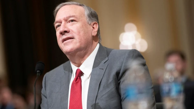 Mike Pompeo, với mái tóc xám gọn gàng chải lệch sang bên, mặc bộ vest xám, áo sơ mi trắng và cà vạt đỏ khi ông làm chứng trước Ủy ban Lựa chọn Hạ viện ở Washington.