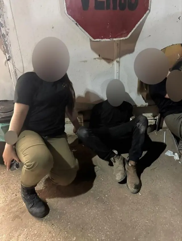 Una foto de un hombre y un joven en un cuarto. Uno de ellos tiene vestimenta militar 