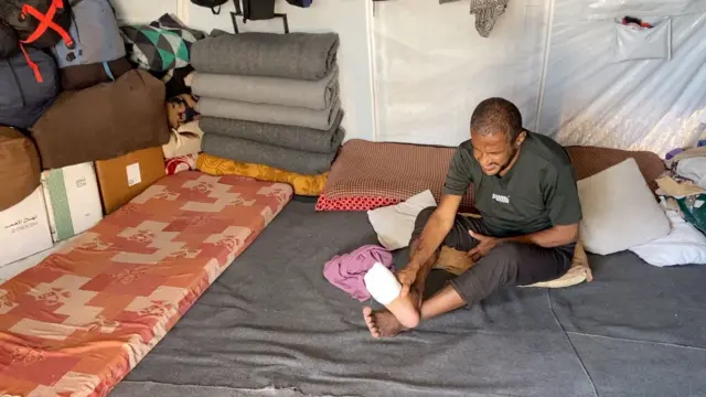 باسل الدحنون يتلمس قدمه المضمدة بعد أن نهش فأر إصبعه.