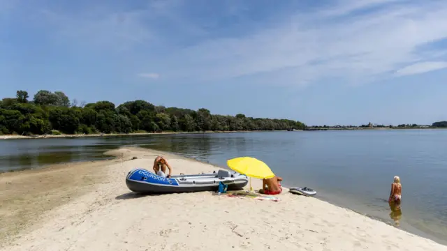 Trójka plażowiczów na nowo odsłoniętych piaszczystych łachach na Dunaju w pobliżu serbskiej miejscowości Apatin.