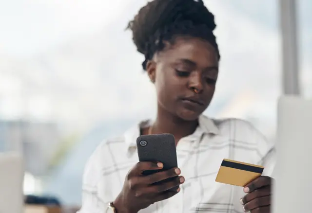 Une femme qui utilise sa carte bancaire et son téléphone portable