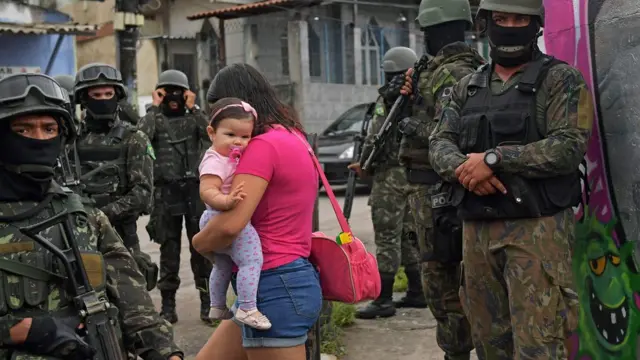 Mulher passa por soldados com crianças no colo