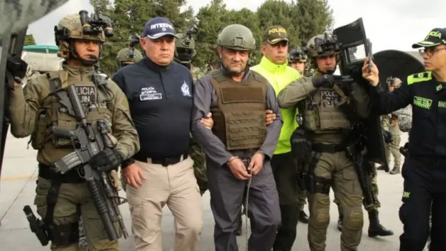 Alias Otoniel esposado y rodeado de policias