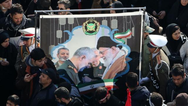 Mourners hold up a picture of Iran's supreme leader and Qasem Soleimani
