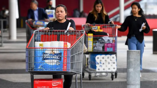 Shoppers leave a supermarket in Melbourne stocked up on toilet roll