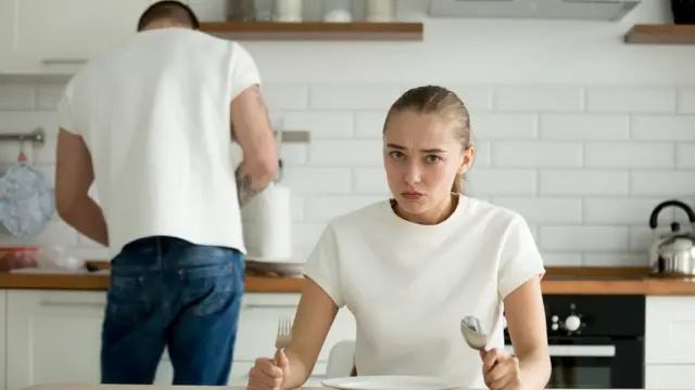 Una mujer esperando en una mesa con los cubiertos