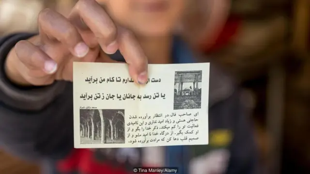 คนถือกระดาษที่มีตัวหนังสือเขียนอยู่