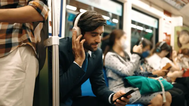 Młody mężczyzna w garniturze, siedzi w metrze i słucha muzyki