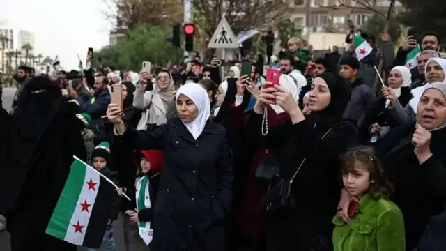 تعدادی زن و کودک و مرد در حال تماشای مراسم رژه نظامی