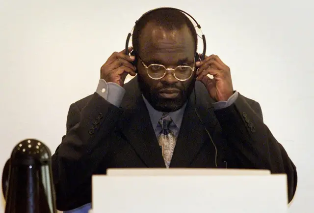 Rwandas's former prime minister Jean Kambanda adjusts the headphones during his trial at the UN war crimes court in The Hague