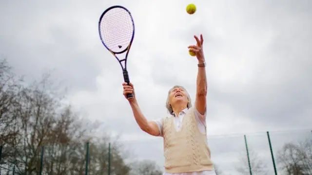 Idosa se prepara para sacar em partida de tênis