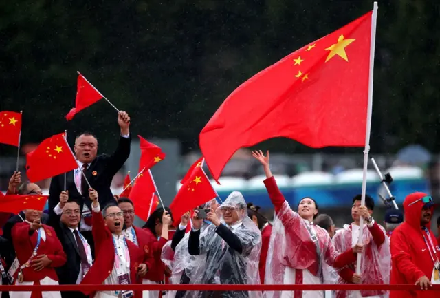Les porte-drapeaux Yu Feng (Chine) et Long Ma (Chine) agitent leur drapeau sur le bateau de l'équipe le long de la Seine.