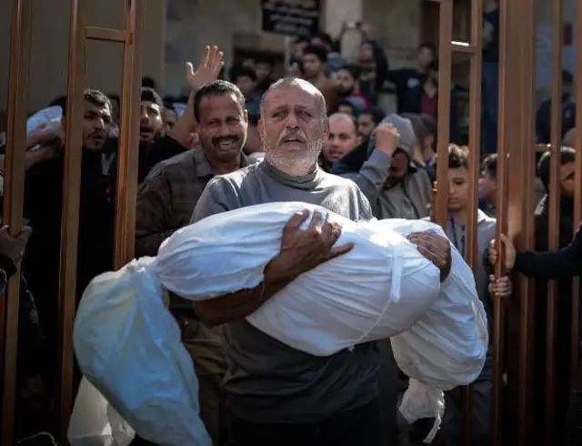 مواطن من مدينة خان يونس يحمل جثمان طفله الذي قضى في غارة إسرائيلية