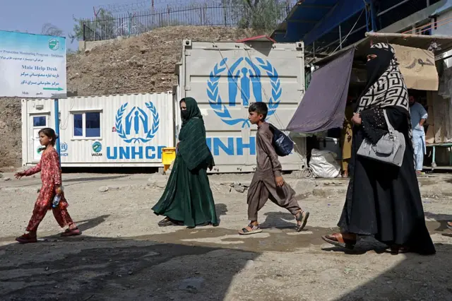 Afganistan-Pakistan arasındaki Torkham sınır kapısından ülkelerine dönen Afgan kadın ve çocuk göçmenler. Arkada Birleşmiş Milletler Mülteciler Yüksek Komiserliği'ne ait kulübeler var. 
