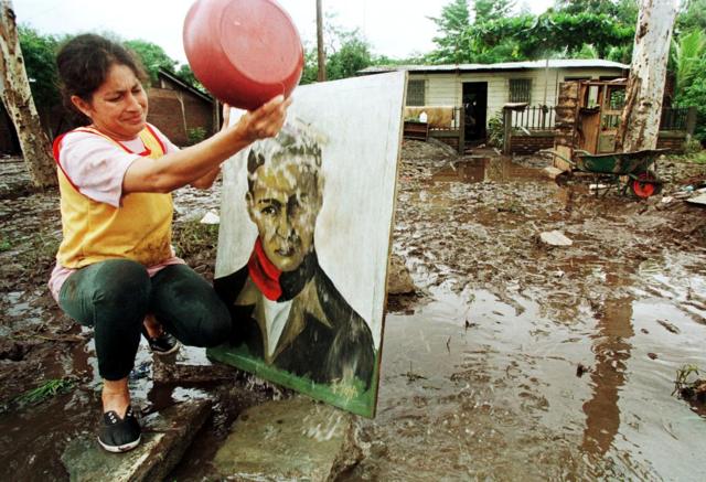 Una mujer nicaragüense limpia de barro el retrato de Sandino tras sufrir los estragos del huracán Mitch en 1998