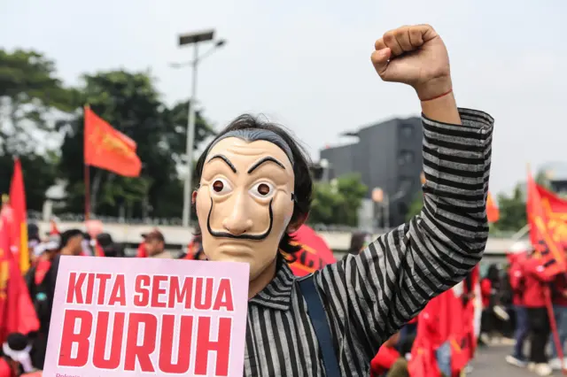 Seorang pengunjuk rasa mengenakan topeng saat aksi memperingati Hari Buruh Internasional di depan Gedung DPR, Senayan, Jakarta, Kamis (1/5/2025).
